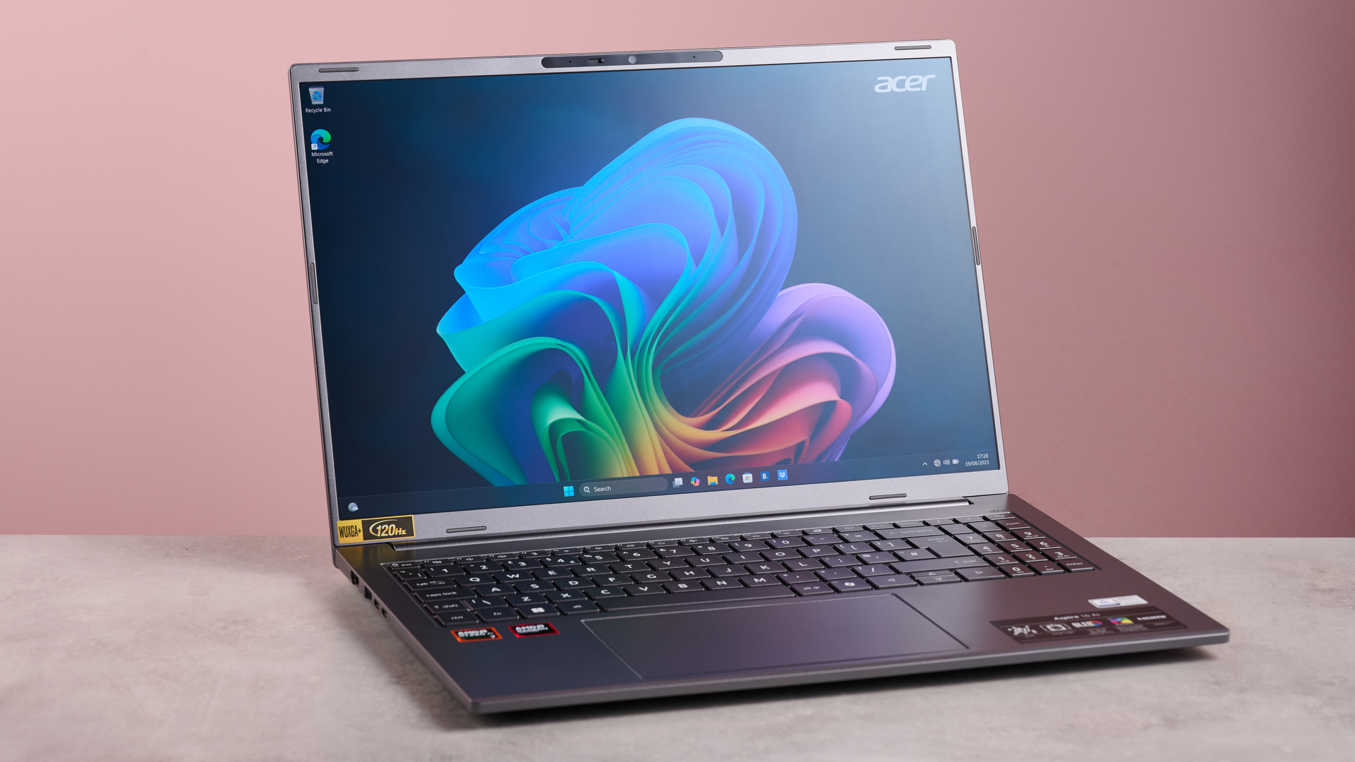 Acer Aspire 16 AI open on table with pink background