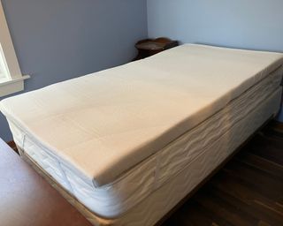 Tempur-Pedic mattress topper installed on mattress and bed frame in bedroom with wooden floor and blue wall paint decor