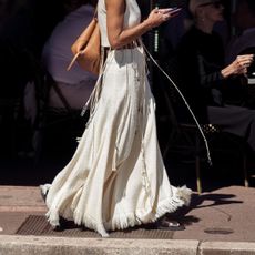 street style shot of woman wearing white fringed maxi skirt