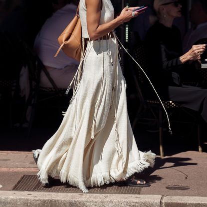street style shot of woman wearing white fringed maxi skirt