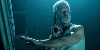 Stephen Lang feeling his surroundings, with a gun in his hand, in Don't Breathe.