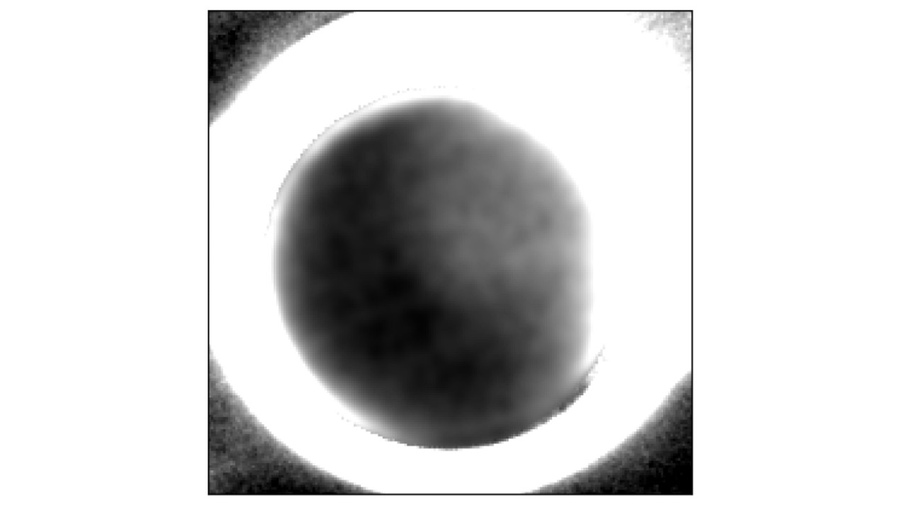 Grainy black and white image showing a dark pluto surrounded by a 
