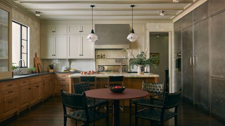 a large two tone kitchen with lower wooden cabinets, upper cream cabinets and a run of stainless steel storage