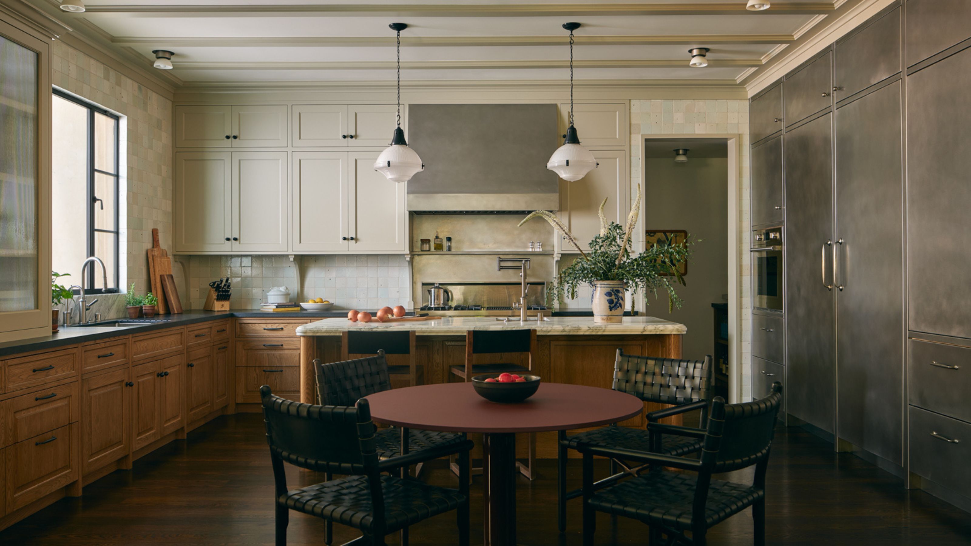 a large two tone kitchen with lower wooden cabinets, upper cream cabinets and a run of stainless steel storage