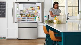 A woman unpacking groceries into her Frigidaire fridge