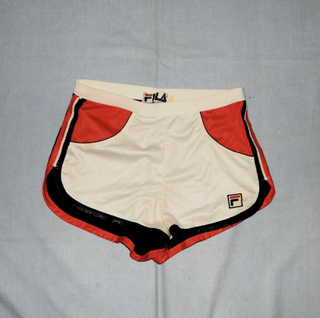a pair of colorblock fila running shorts laying on a plain backdrop