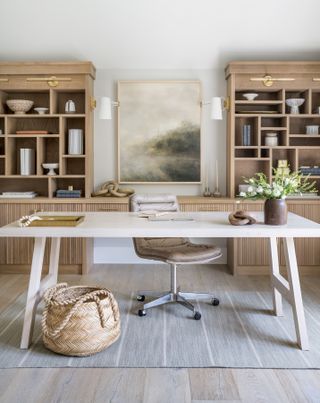 home office for her with white desk, two shelving units, artwork, baskets, office chair, rug
