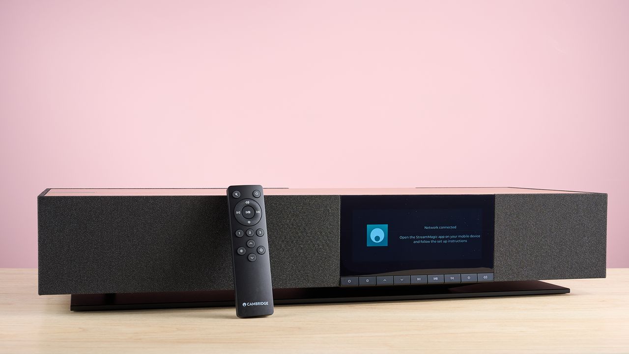 The Cambridge Audio Evo One viewed from the front showing its low profile. Its remote leans against it, showing the small size of the remote, which is a black plastic rectangle.