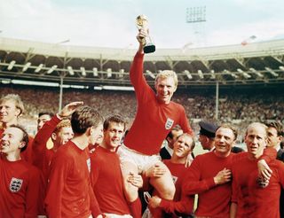 England captain Bobby Moore lifted by his team-mates as he holds aloft the Jules Rimet trophy following the Three Lions' World Cup final win over West Germany in 1966.