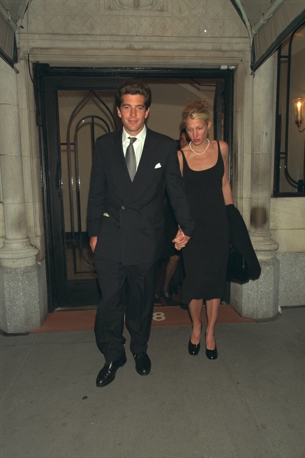 Carolyn Bessette-Kennedy wears a knee-length skirt and high-vamp pumps.