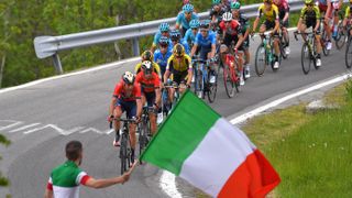 Giro d'Italia cyclists egged on by local man waving 2ft Italian flag on a wooden pole.