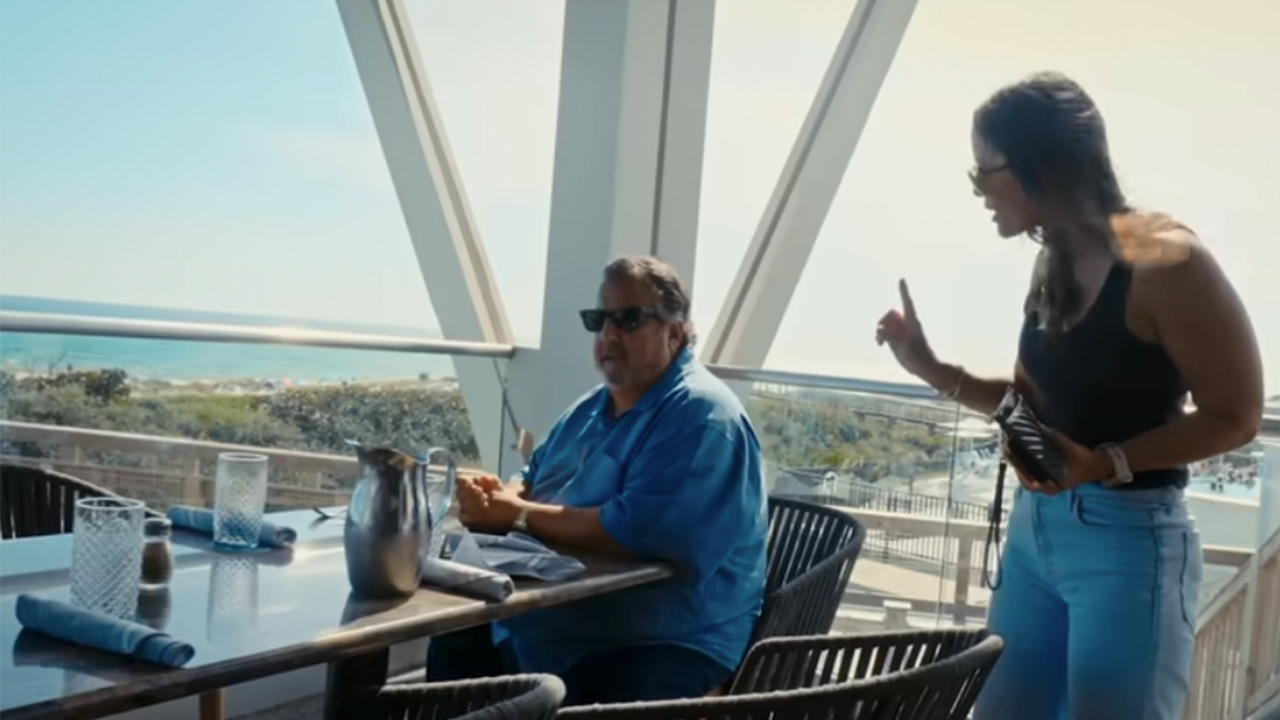 ネイバーズで座っている男性に向かって指を振る女性。