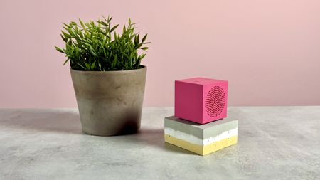 The Ikea Kallsup in Hot Pink on top of a grey, white and yellow slab of concrete next to a pot plant.