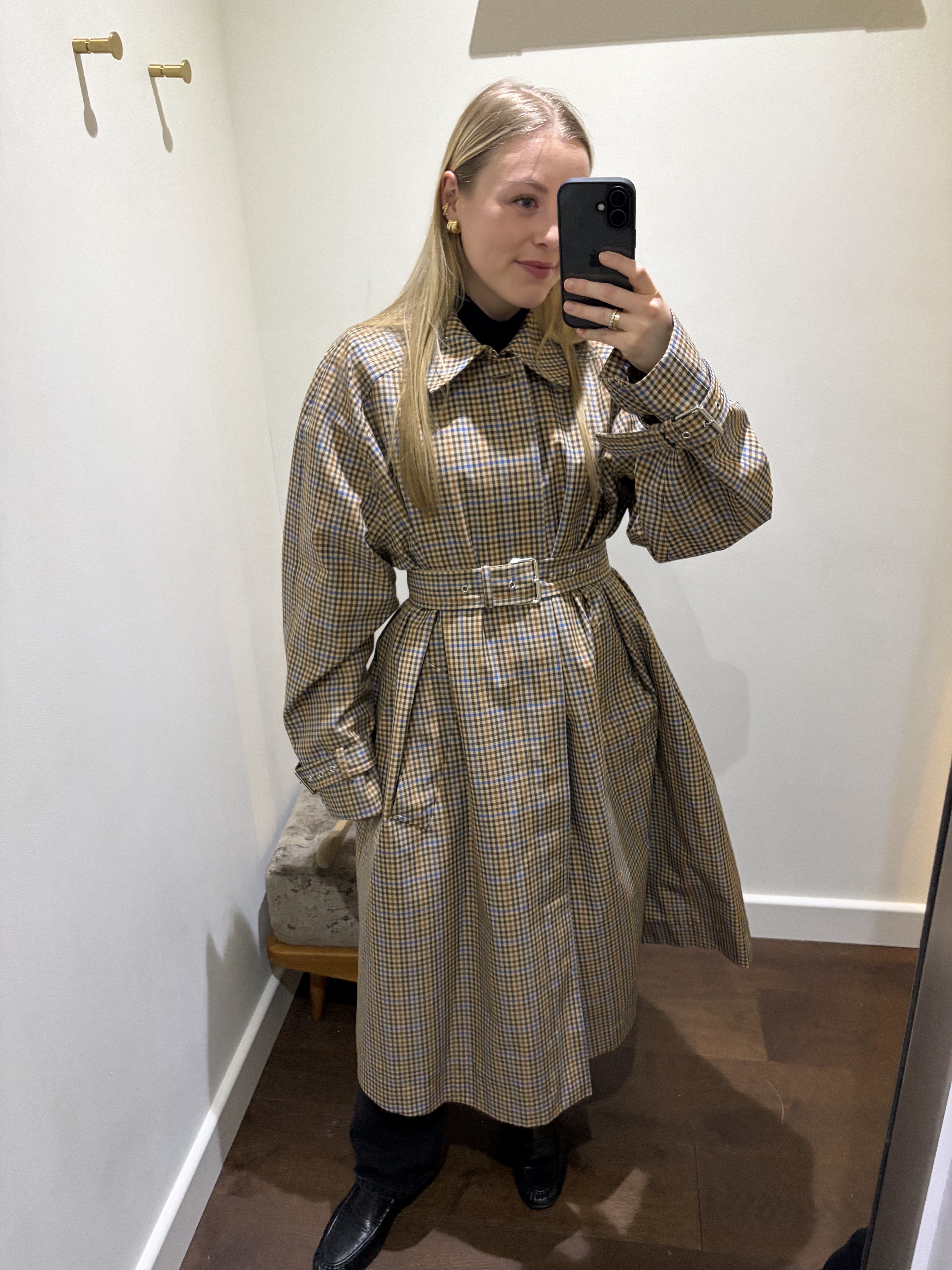 Woman wears check trench coat, black jeans, black loafers