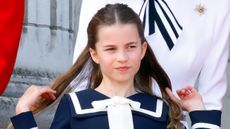 Princess Charlotte flips back her hair as she watches an RAF flypast from the balcony of Buckingham Palace after attending Trooping the Colour on June 15, 2024
