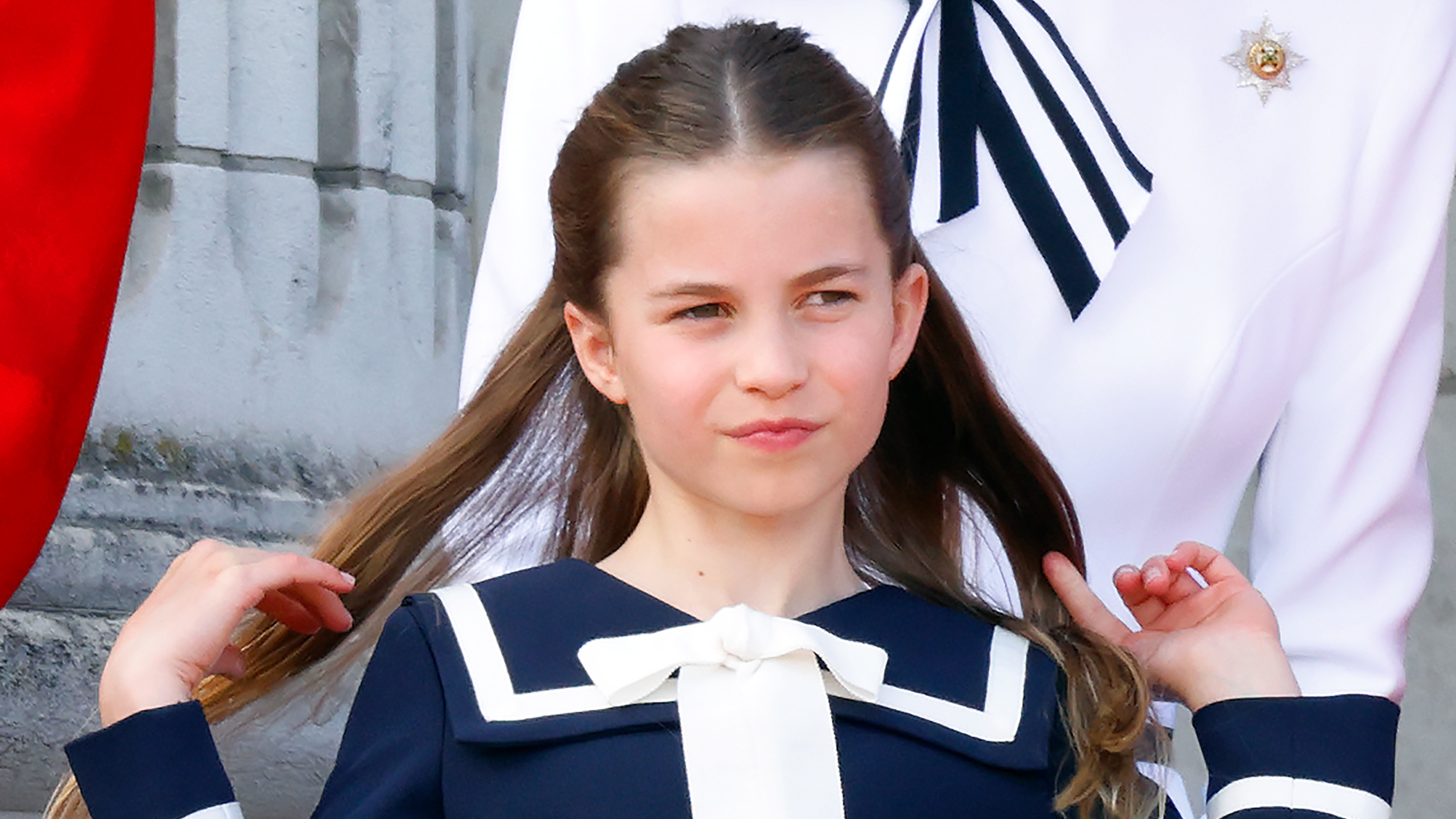 Princess Charlotte flips back her hair as she watches an RAF flypast from the balcony of Buckingham Palace after attending Trooping the Colour on June 15, 2024
