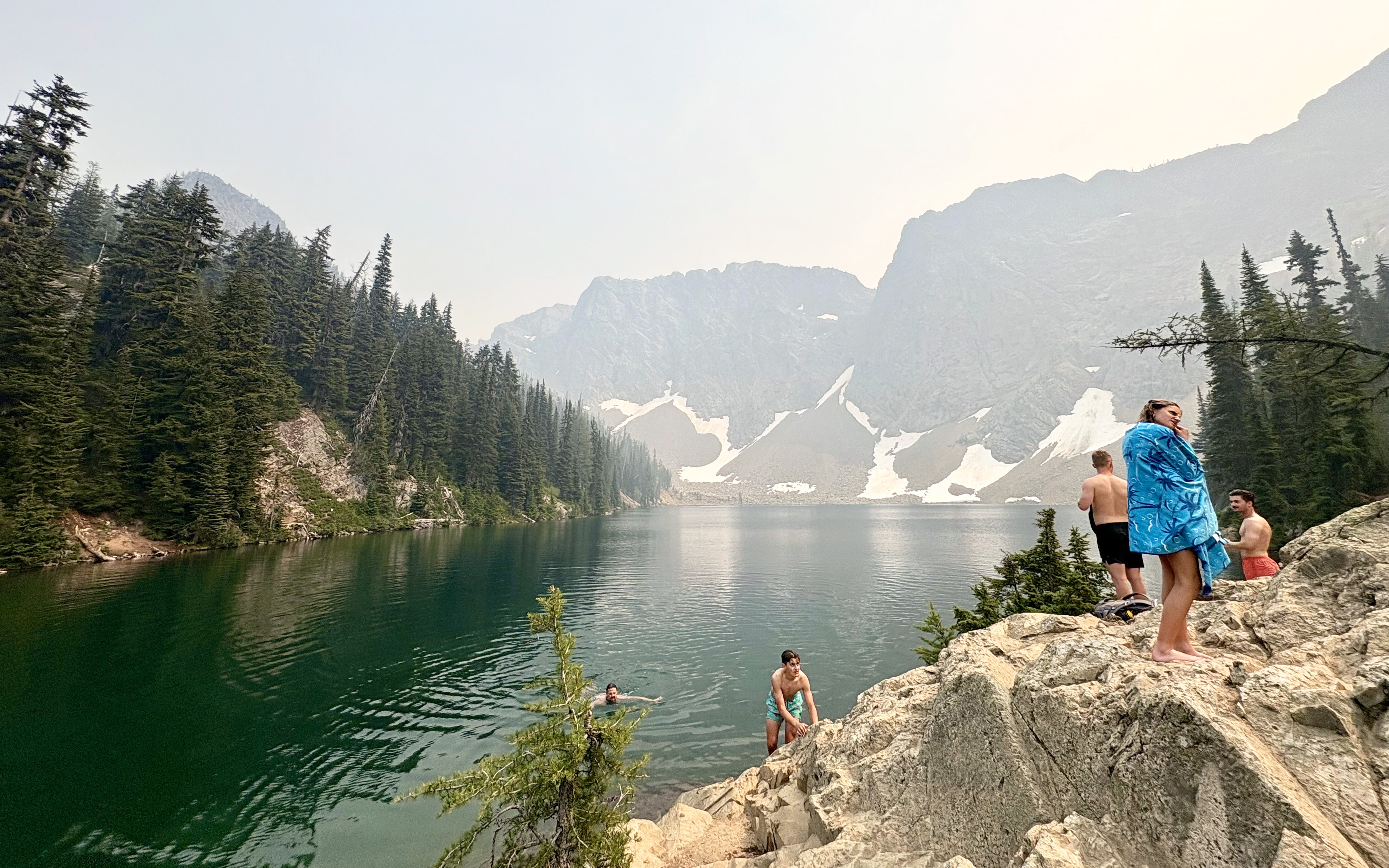 Scenic photo of Blue Lake in the Cascade Mountains with swimmers, glaciers, and trees