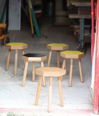 5 wooden three-legged stools with hexagonal seats in black and yellow