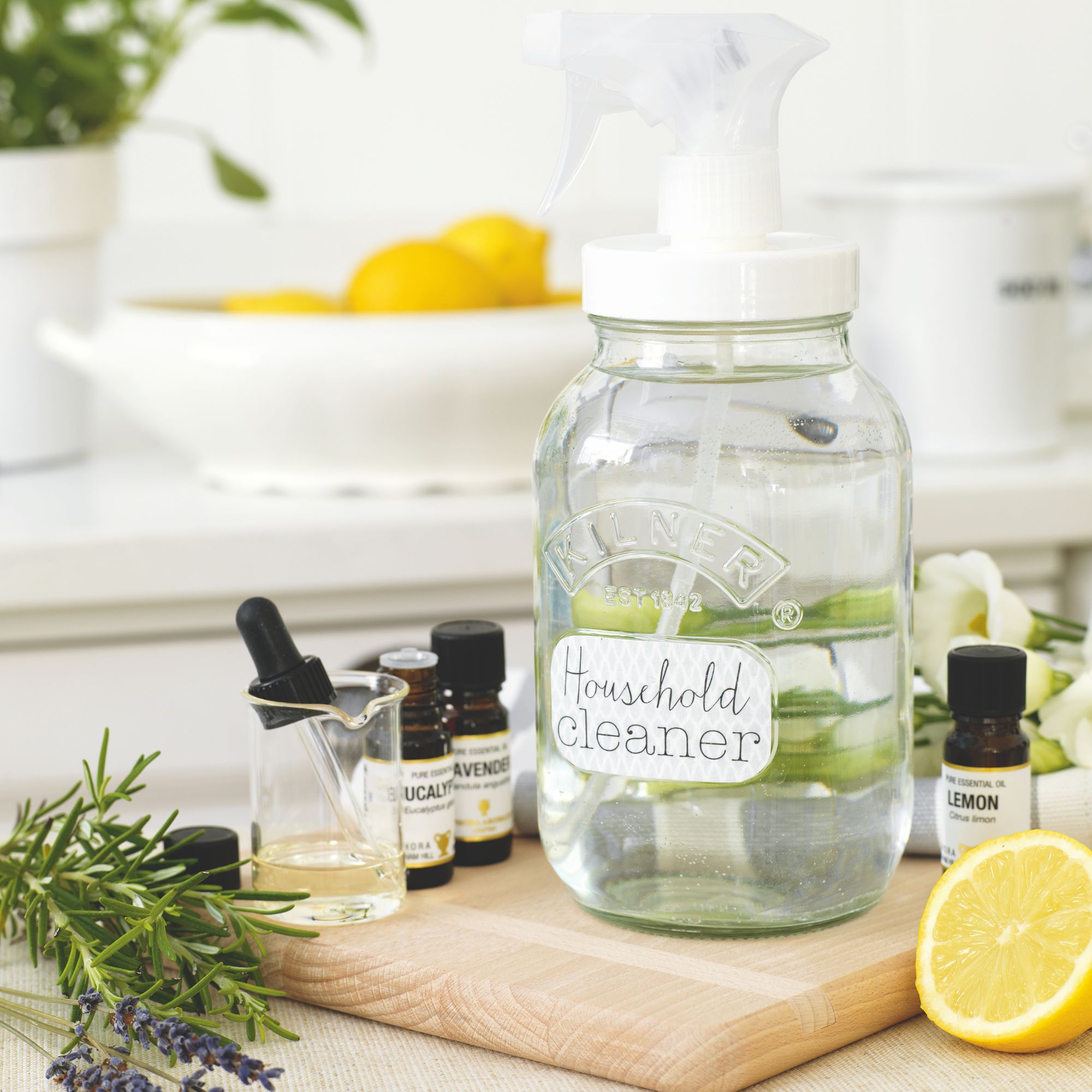 Jar of household cleaner surrounded by lemons, lavender ,and essential oil bottles