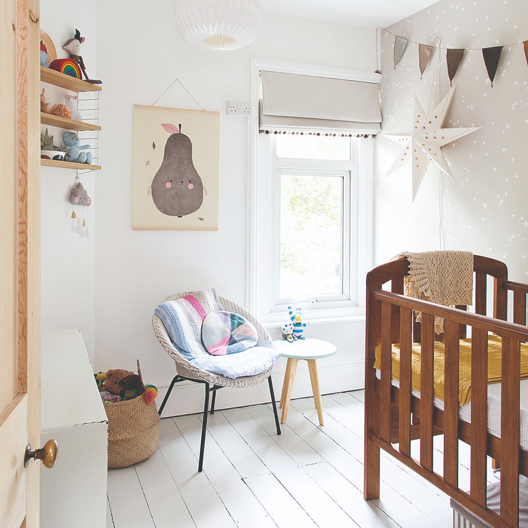 A white minimalist nursery with a wooden cot and a wallpaper-covered feature wall