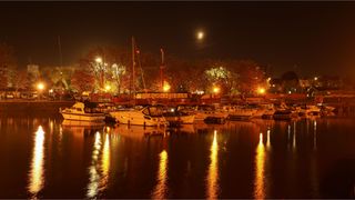 A harbourside at night with boats and street lights