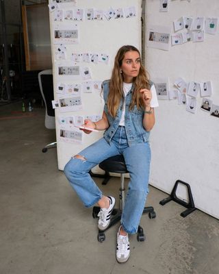 Vee Collective founder Lili Radu wearing a denim vest with a white tee, jeans, and Adidas Sambas