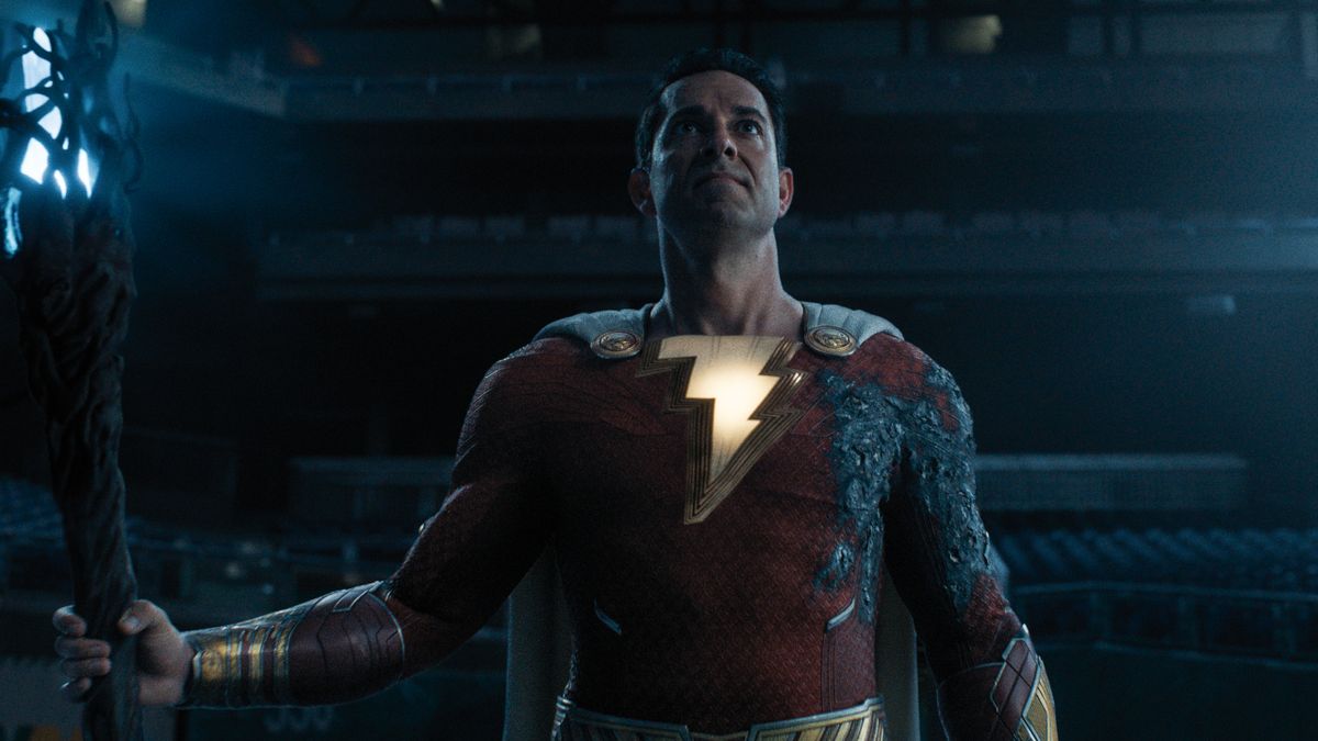 Zachary Levi stands in a baseball stadium holding a powerful staff in Shazam! Fury of the Gods.