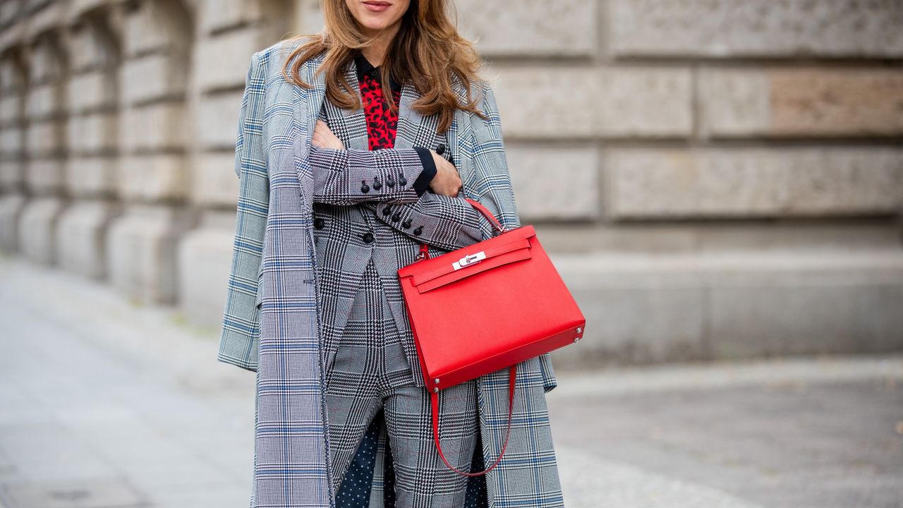 Woman sporting a red Birkin while posing on the streets during Berlin Fashion Week.