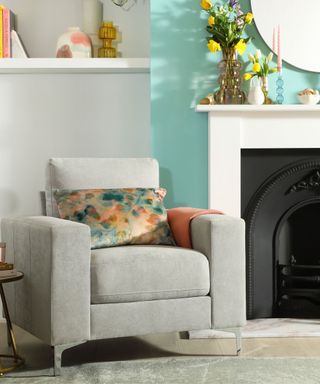 A gray and aqua living room with a white fireplace and gray armchair