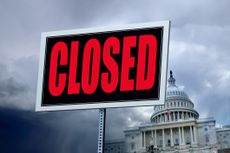 A closed sign in front of the United States Capitol building.