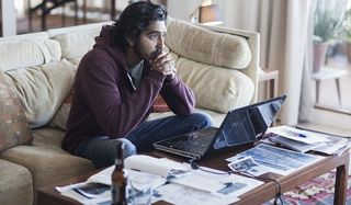 Lion Dev Patel sitting stoically in front of his computer