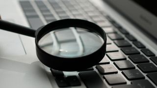 a magnifying glass held above a laptop keyboard