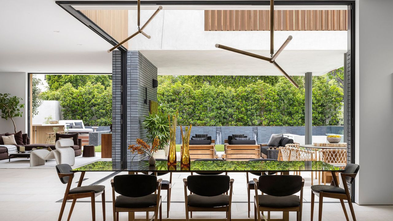 A dining table and living room space with an open floor plan looking out to the outdoor living area