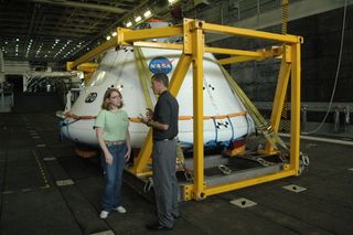 Seen next to the Orion test article are Brandi Dean, NASA spokesperson, and Jeremy Graeber, the NASA test director. The boilerplate Orion test article is basically an unfinished shell with the hatch and maneuvering thrusters merely painted on.