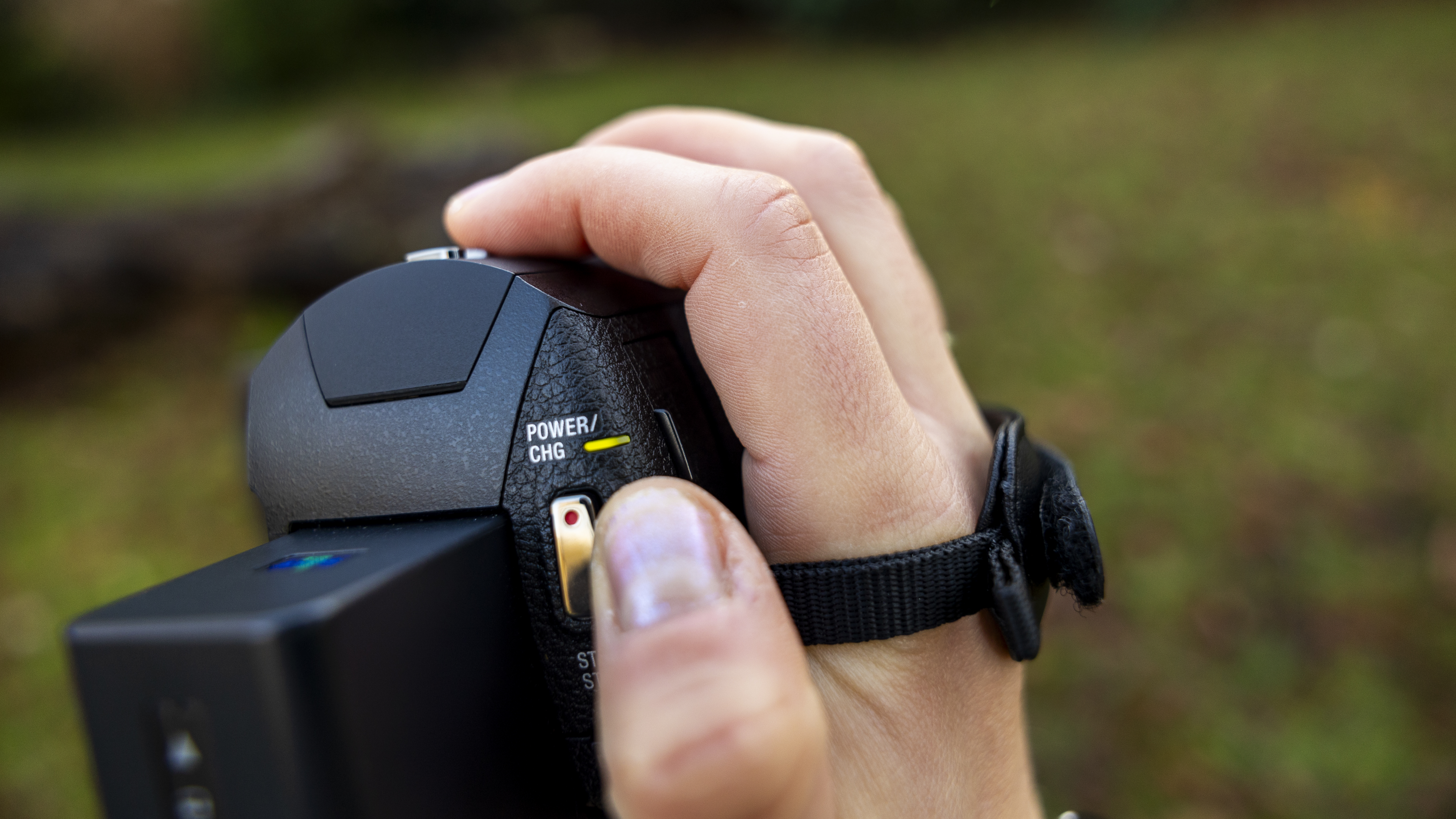 A photographer holding the Sony AX43 by the wrist strap