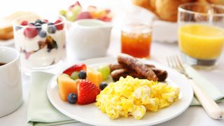 A breakfast plate filled with egg, sausage and fruit