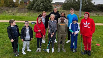 A group of kids learning to play golf