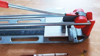 Close up of manual tile cutter cutting a white metro tile