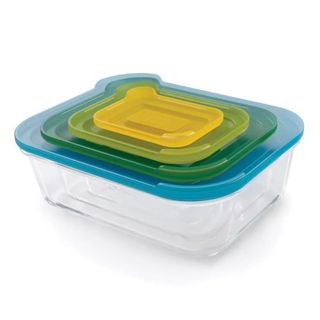 Four glass containers of different sizes are nested within each other, with different colored lids