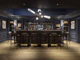 A dark themed basement with a modern bar