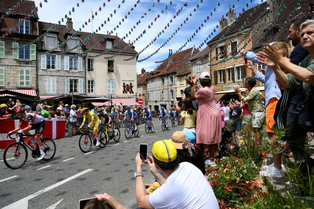 LAUSANNE SWITZERLAND JULY 09 Tadej Pogacar of Slovenia and UAE Team Emirates Yellow Leader Jersey and a general view of the Peloton passing through Arbois Village while fans cheer during the 109th Tour de France 2022 Stage 8 a 1863km stage from Dole to Lausanne Cte du Stade olympique 602m TDF2022 WorldTour on July 09 2022 in Lausanne Switzerland Photo by Alex BroadwayGetty Images