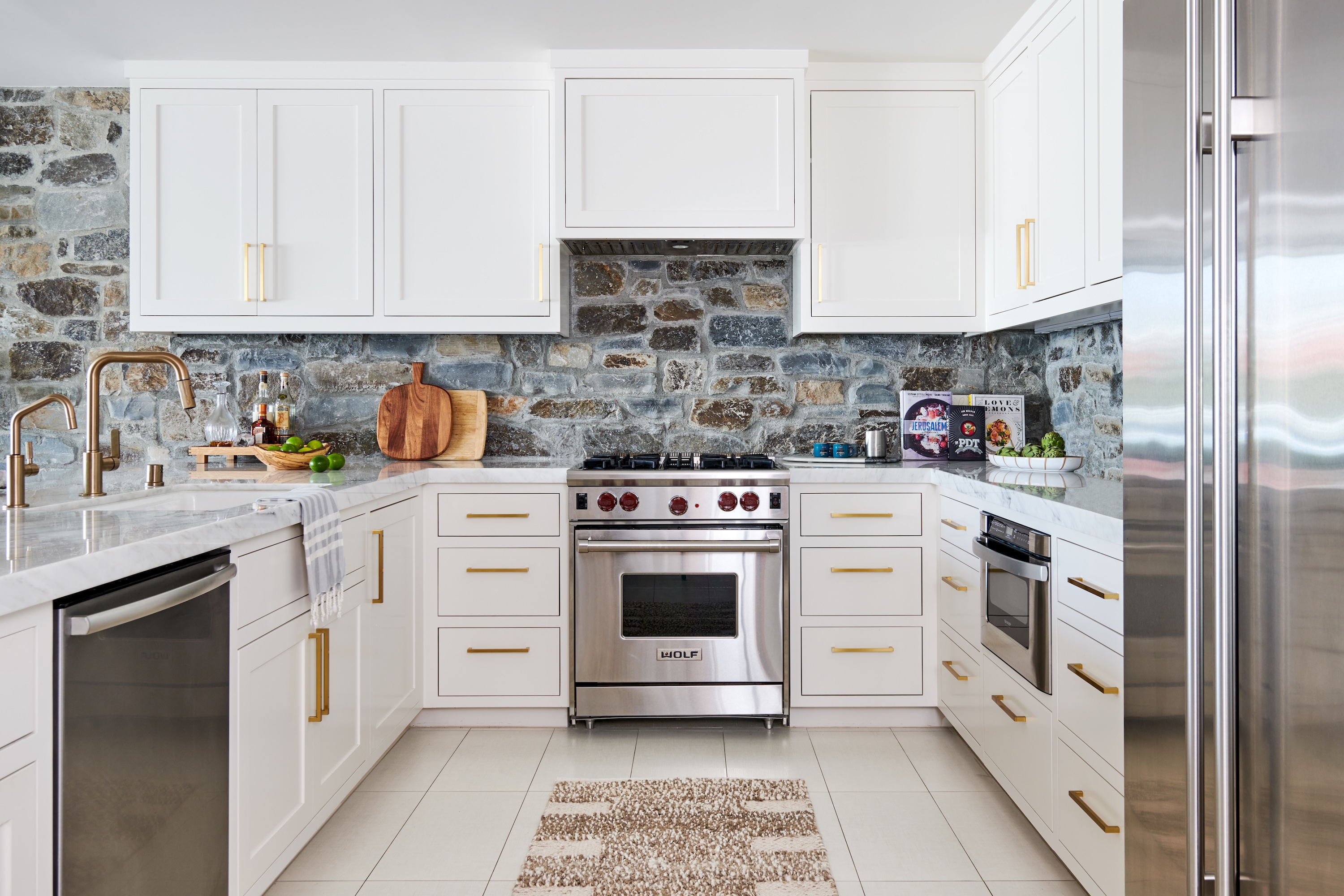 A white kitchen with a grey stone surface backsplash and wall carried through the build