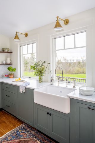 belfast sink in green cabinetry under window in kitchen
