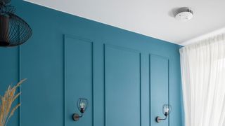 FireAngel smart fire alarm on whit ceiling with blue panelled walls