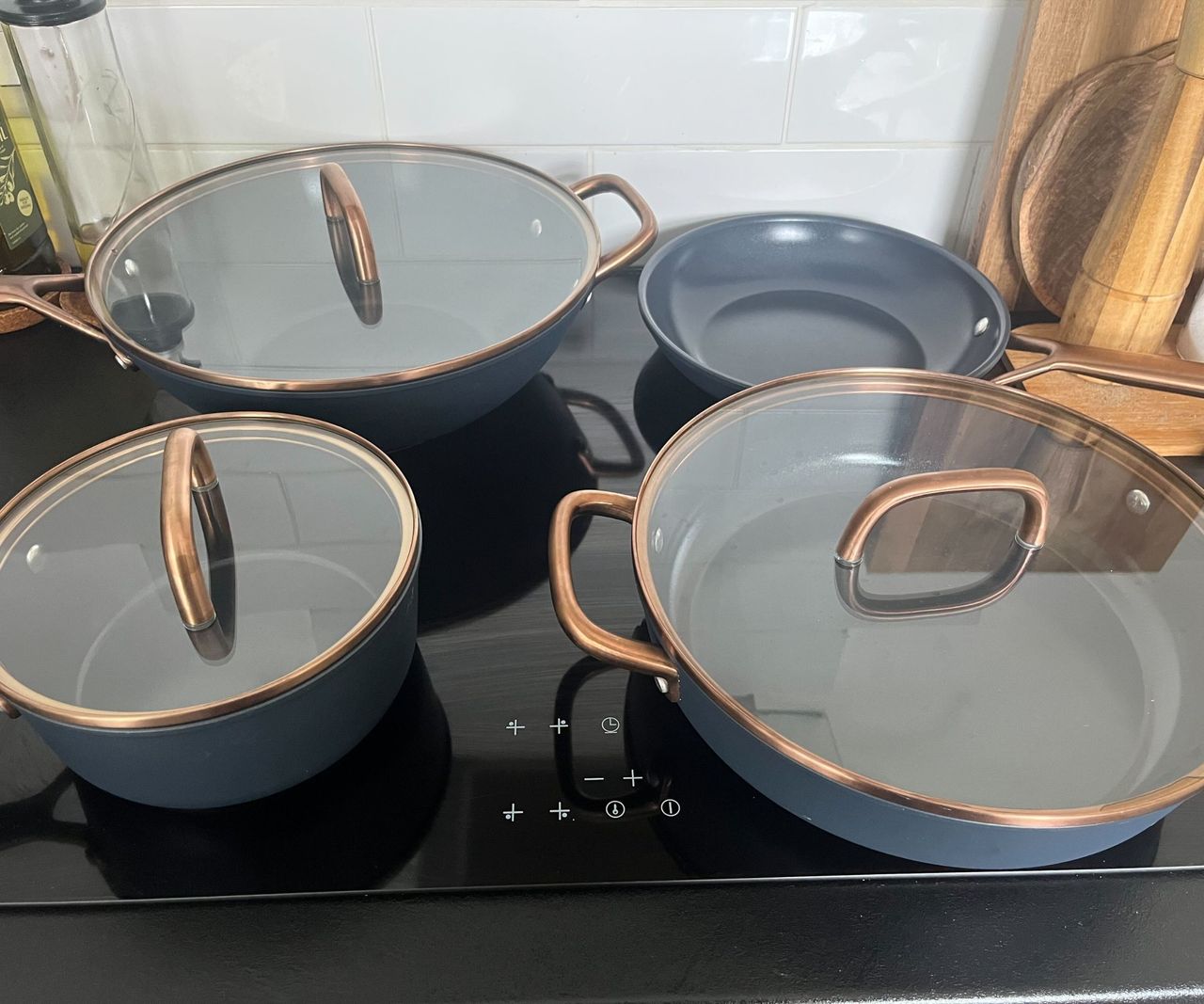 Blue ceramic pans with glass lids on a black hob