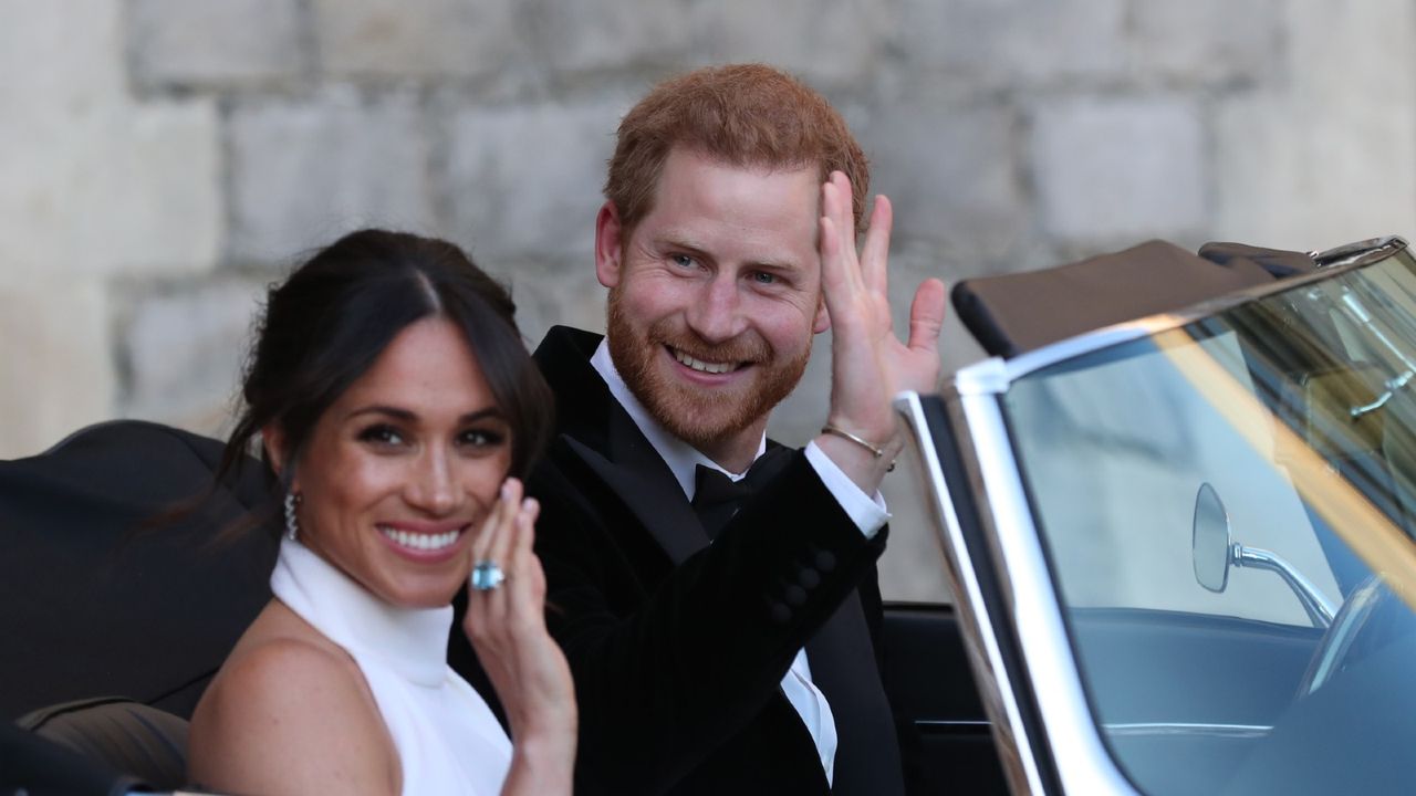 Britain&#039;s Prince Harry, Duke of Sussex, (R) and Meghan Markle, Duchess of Sussex, (L) leave Windsor Castle in Windsor on May 19, 2018 in an E-Type Jaguar after their wedding to attend an evening reception at Frogmore House.