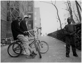 Black and white photo of two boys sitting on their bicycles.