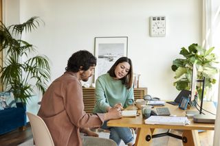 A man and a woman organising their plans together in their home office.