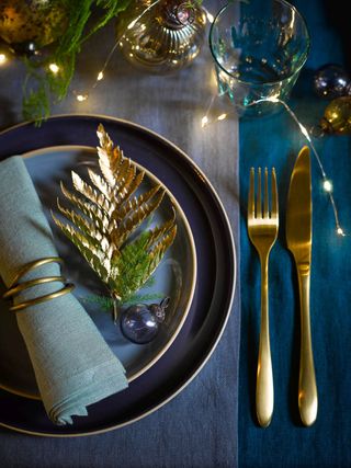 New Year table decor with blue tablecloth and gold cutlery