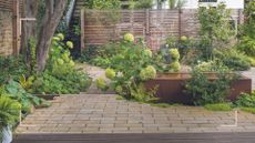 Garden with brick patio and raised bed with planting to support expert advice on when to prune hydrangeas